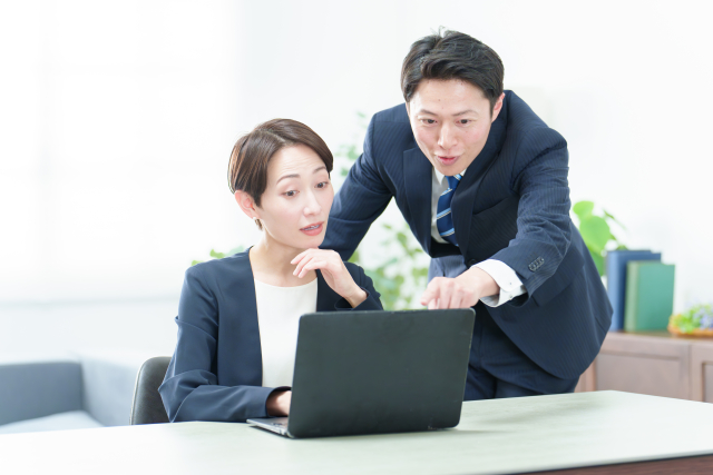 女性上司が苦手なのは甘えじゃないのアイキャッチ｜男性部下が女性上司のパソコン画面を指差しながら説明し、上司がやや緊張した表情で見つめるオフィスの一コマ
