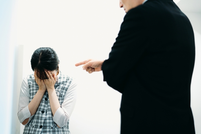 昭和上司がうざいと感じる人向け記事のアイキャッチ｜スーツ姿の男性が指を差して詰め寄り、隣で女性社員が顔を覆ってうずくまる様子。理不尽な叱責・精神論を象徴する一枚。